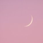 "Croissant de lune fin dans un ciel rosé poudré, symbole de transformation douce et d’introspection"